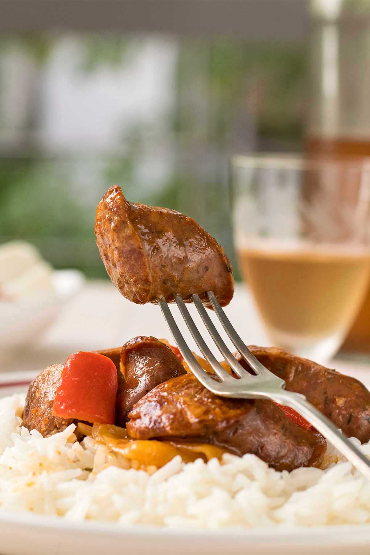 Image of a piece of Greek sausage cooked in a wine sauce with peppers.