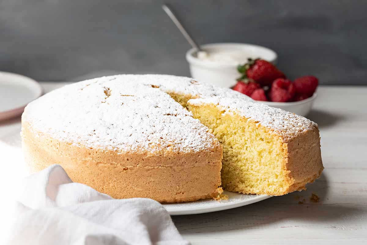 Sliced lemon olive oil cake with red berries on the background.