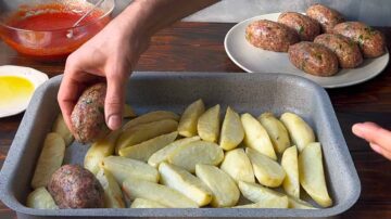 A hand placing the beef patties among the potato wedges.