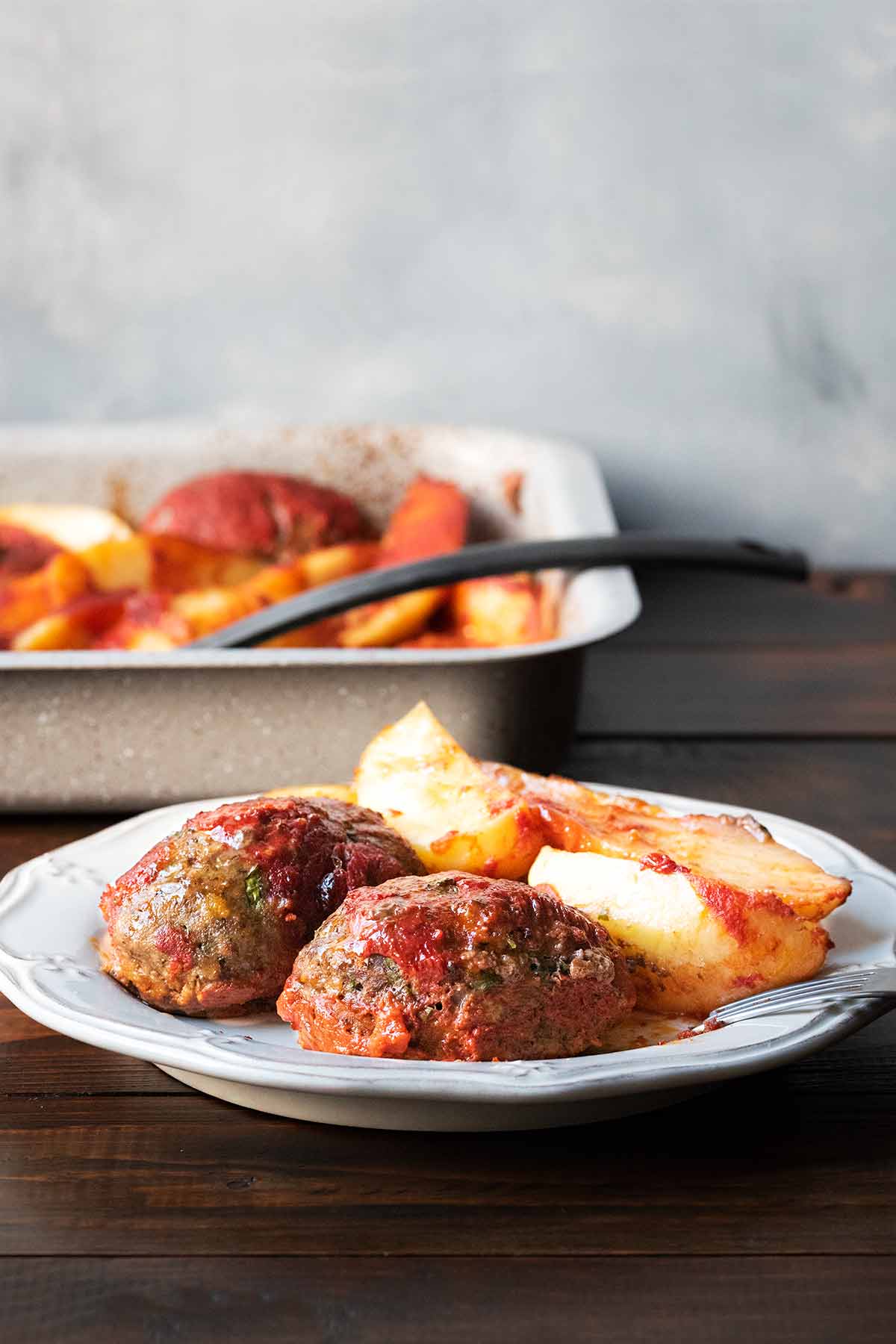 Two Greek bifteki )beef patties) with potatoes on a plate.