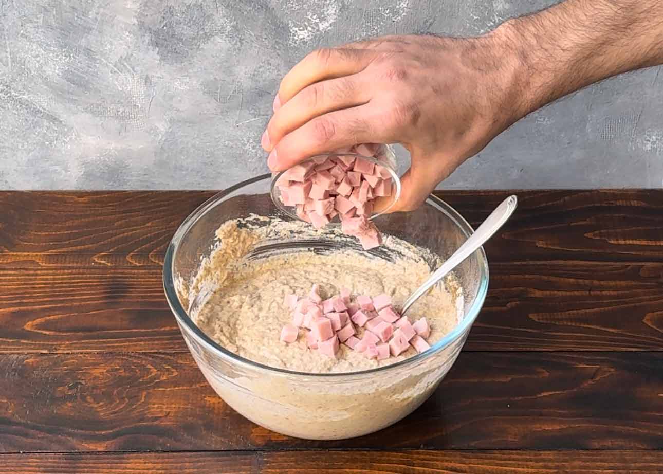 Adding the ham to the muffin mixture.