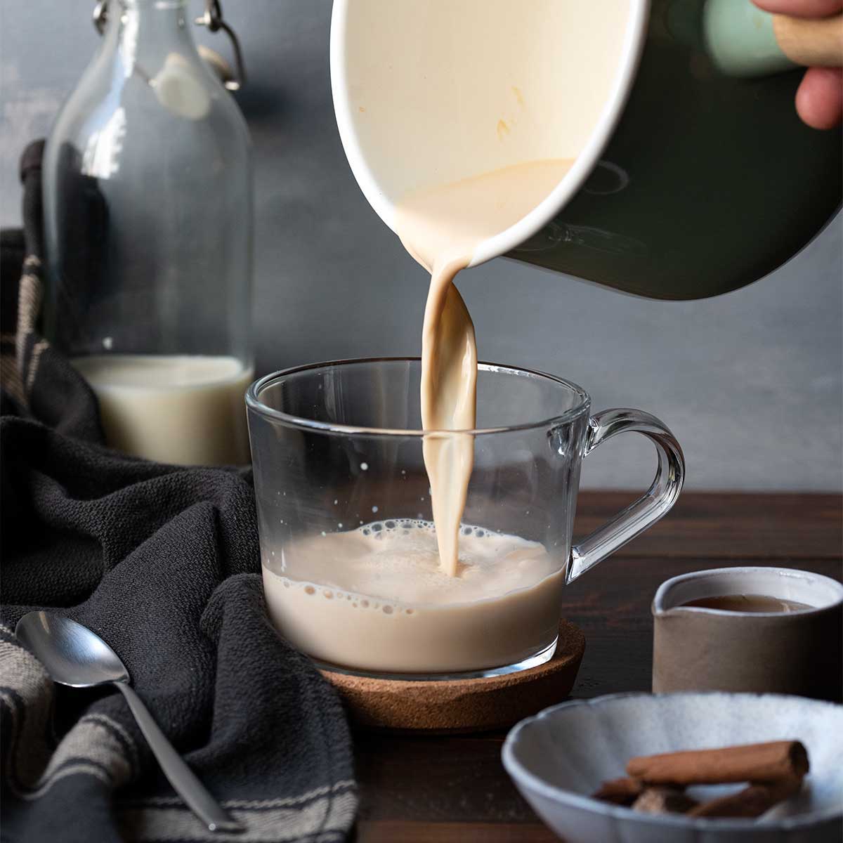 Pouring the hot chai latte into a mug.