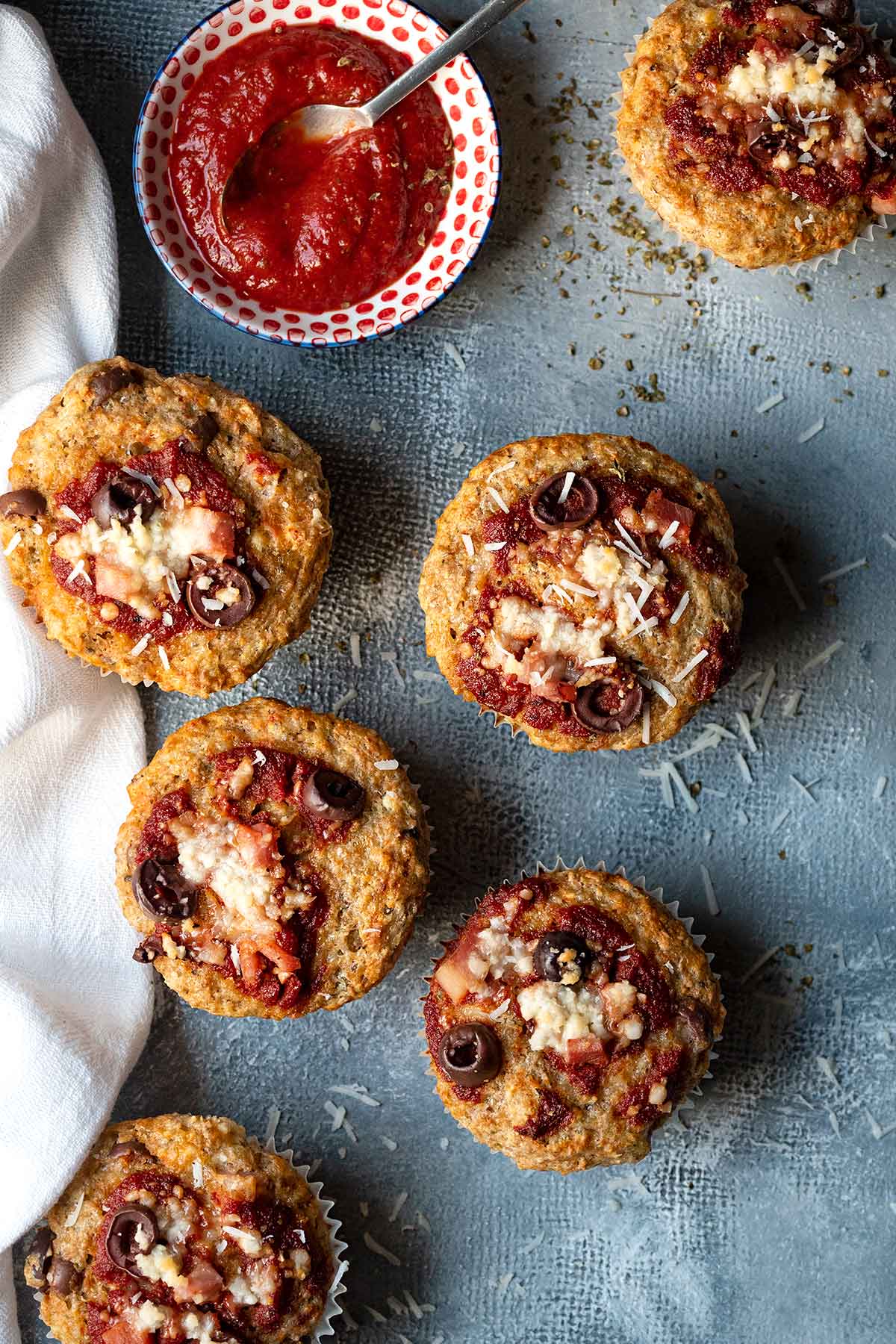 6 savory muffins and a bowl with tomato sauce.
