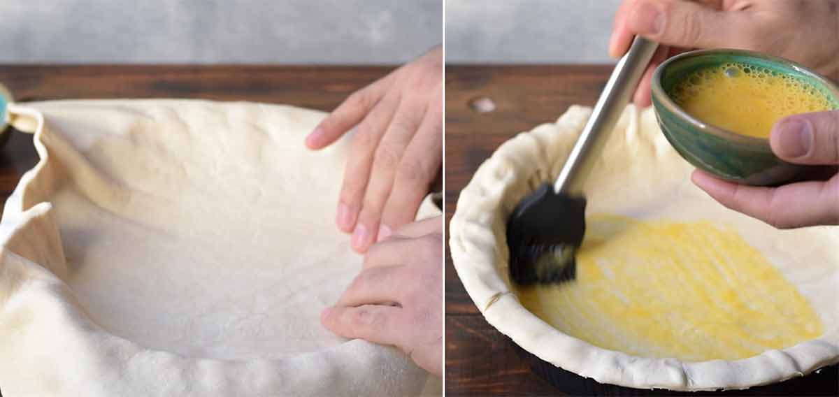 Two hands covering the pie dish with puff pastry and brushing it with egg wash.