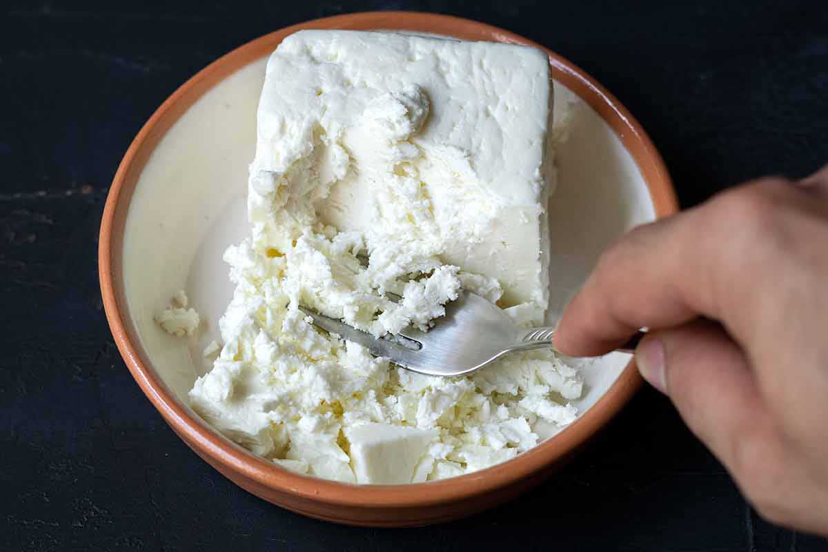 Mashing Greek feta cheese with a fork.