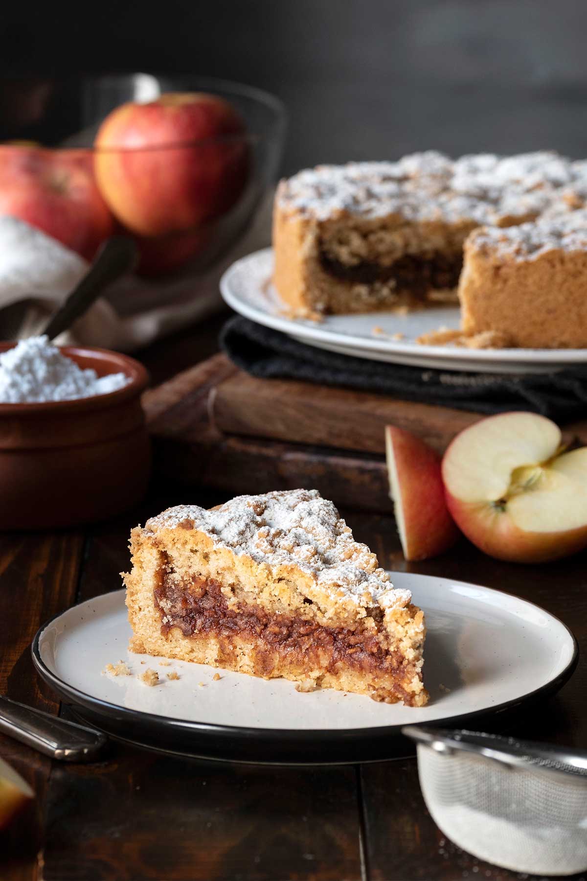 A slice of apple crumb pie next to the whole pie.