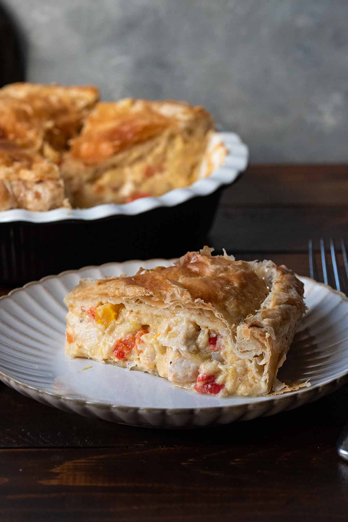 A slice of easy chicken pot pie with puff pastry crust on a plate.