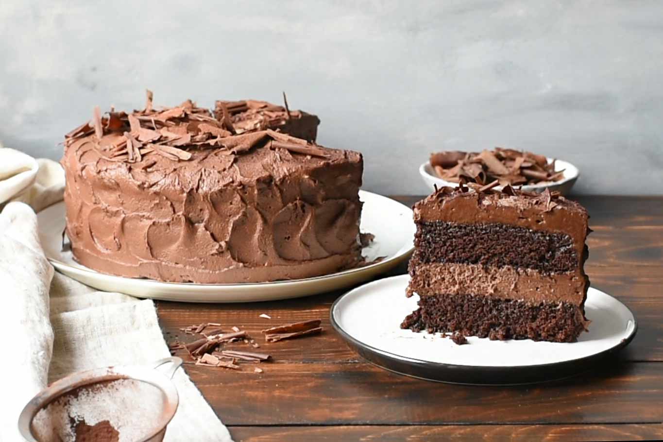 A piece of chocolate cake next to a whole chocolate mousse cake.
