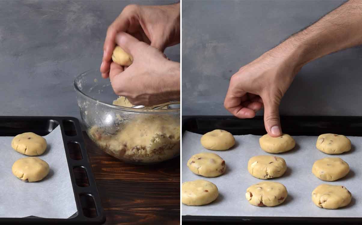 A hand shaping ball with cookie dough and a thumb pressing the center of the cookies on the baking tray.