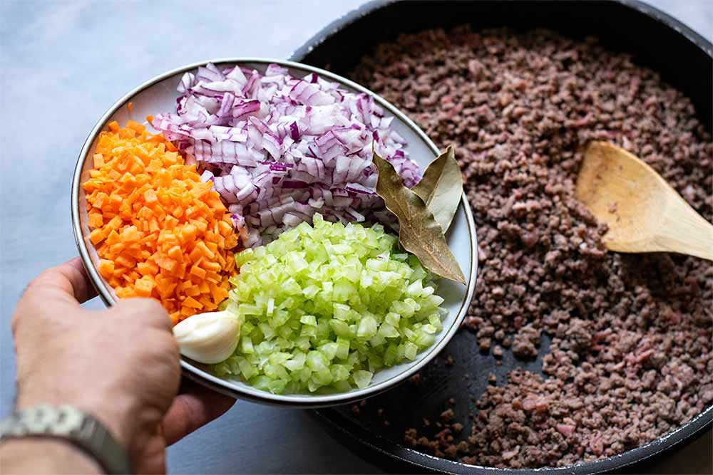 Process shot showing how to add the vegetables after toasting the meat.