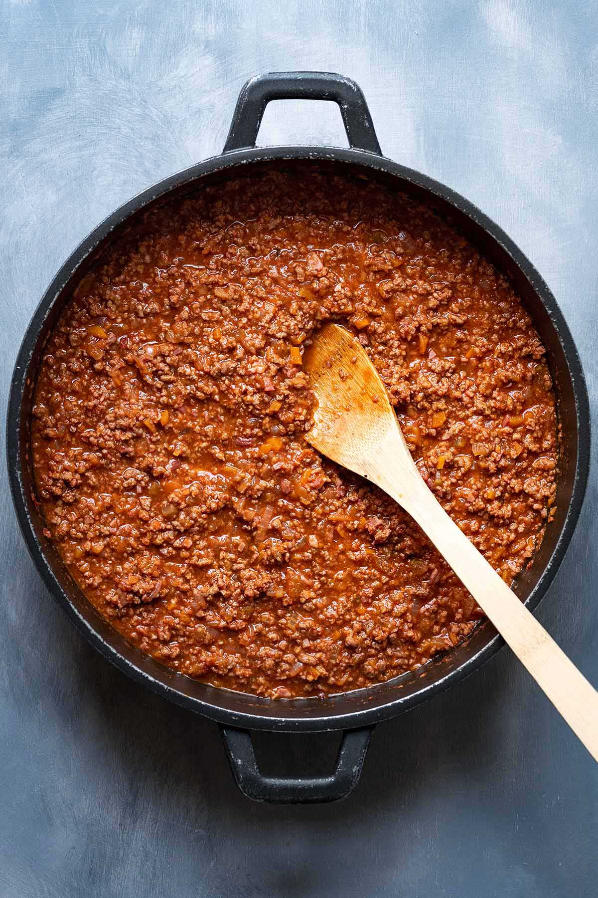 Image showing finished Bolognese sauce in a saucepan with a wooden spoon.