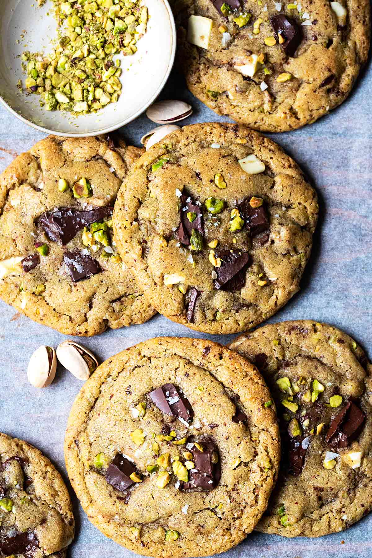 Pistachio chocolate chunk cookies on a piece of parchment paper.