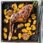 Roasted goat leg in the oven with potatoes. featured image.