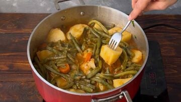 A fork piercing a potato in the pot.