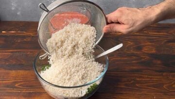 A hand adding the rice to a bowl.
