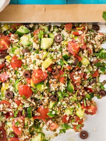 A tray with lentil and bulgur salad with chopped vegetables.
