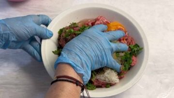 A hand mixing the meatball mixture.