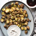 Air fryer Brussels sprouts on a plate served with yogurt sauce.