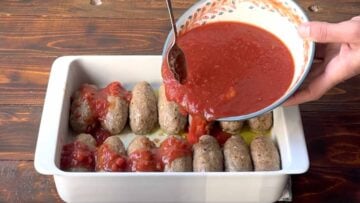 Pouring the tomato sauce over the soutzoukakia.