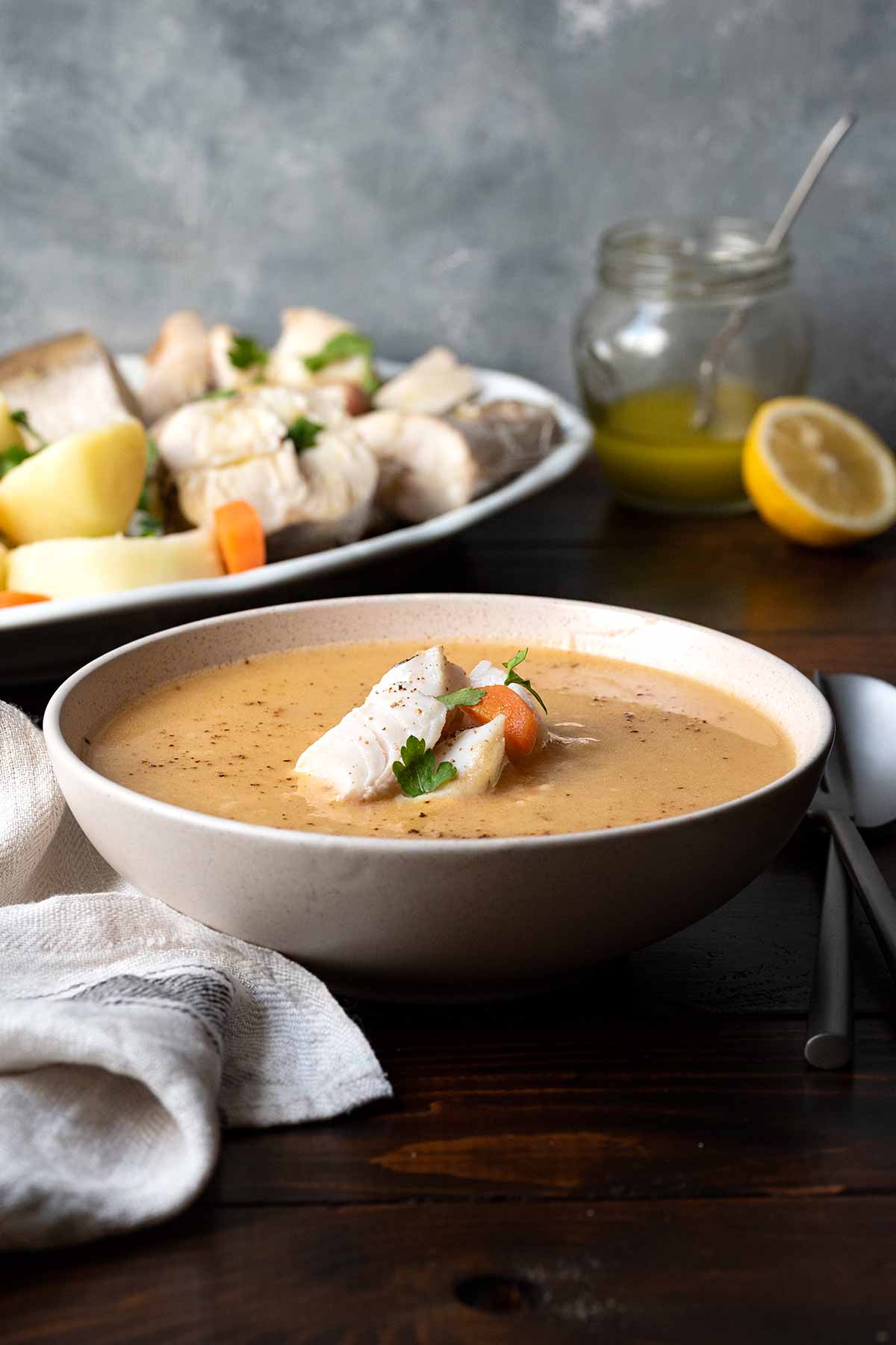 A bowl with Greek fish soup (psarosoupa) and a plate with fish and potatoes.