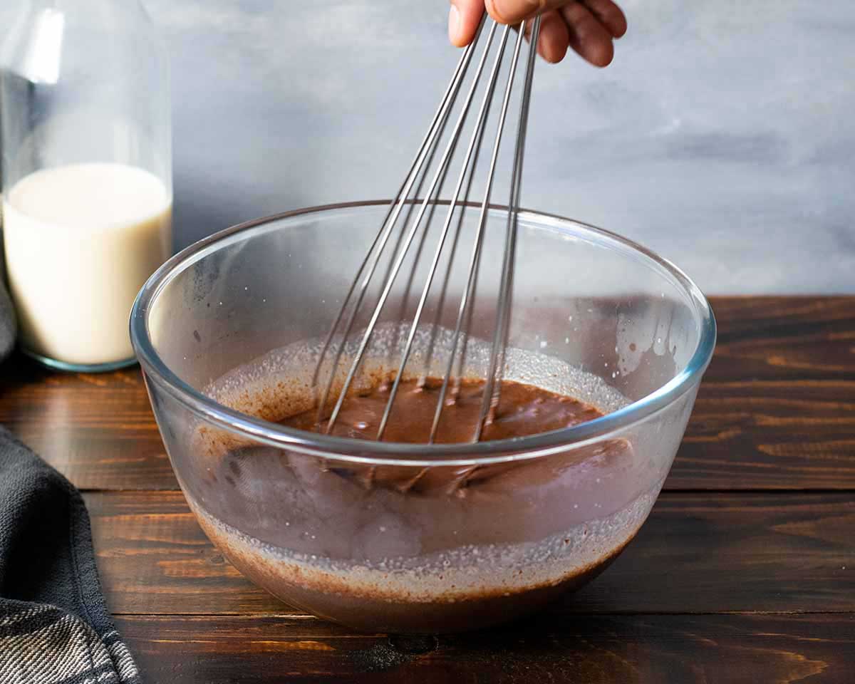 Mixing the chocolate with the hot milk, using a whisk.