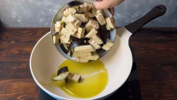 Cubed eggplant in a saucepan with olive oil.