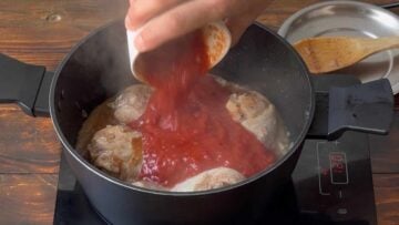 Adding grated tomatoes to the pot.