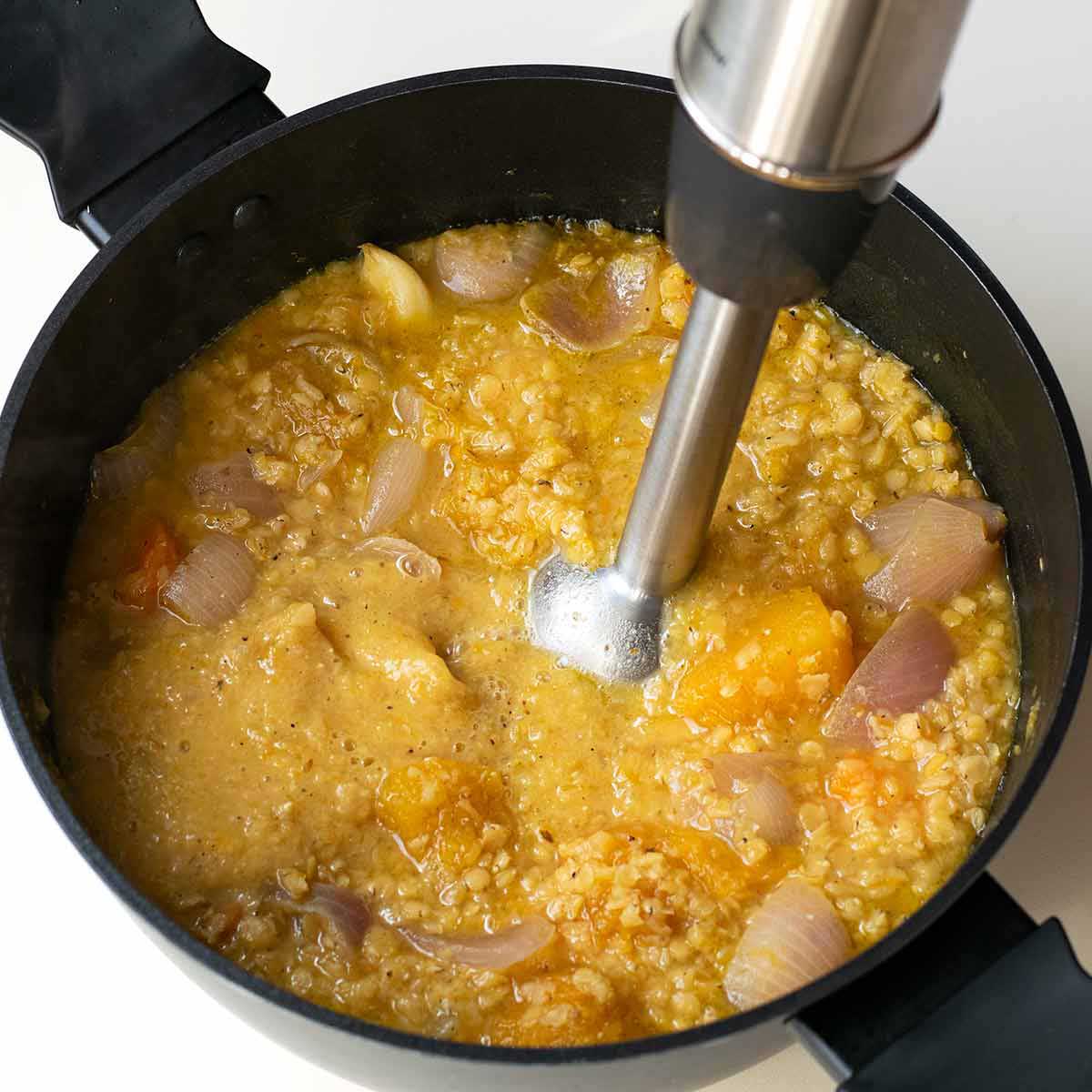 How to blend the pumpkin soup with an immersion blender to make it creamy.