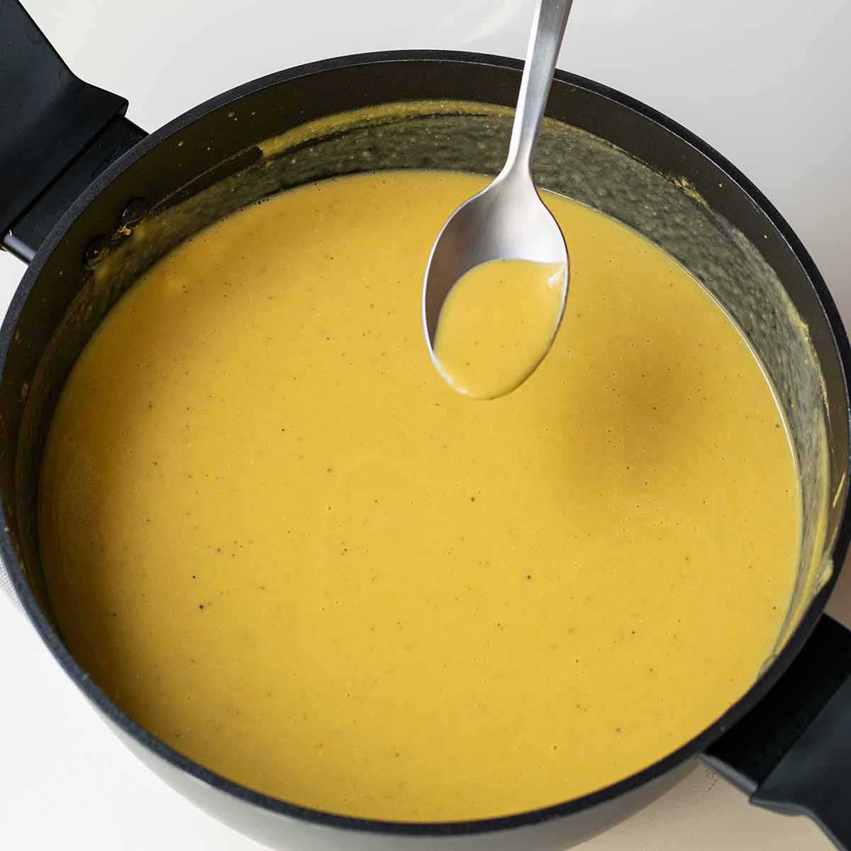 Tasting the finished soup in order to adjust the seasonings.