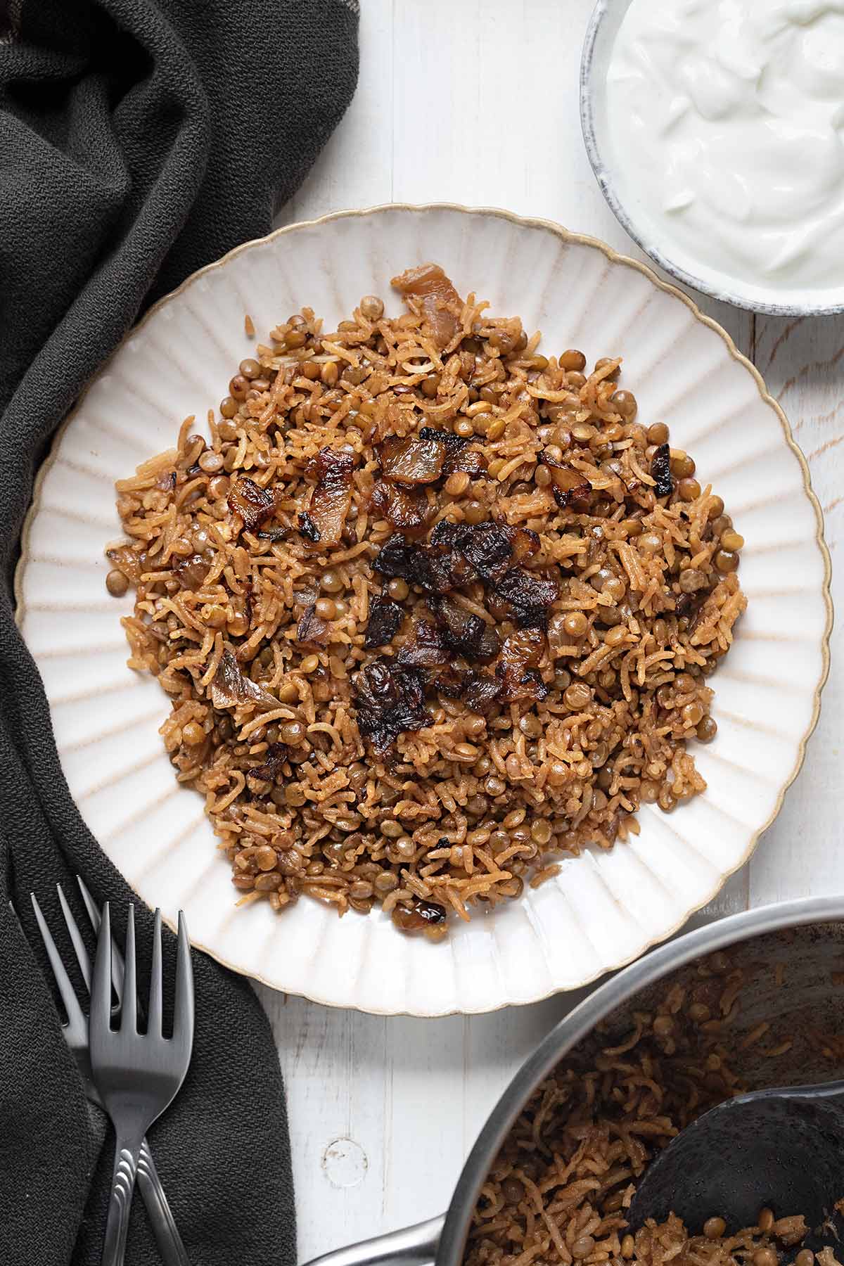 A plate with Lebanese rice and lentils pilaf and a bowl with yogurt.