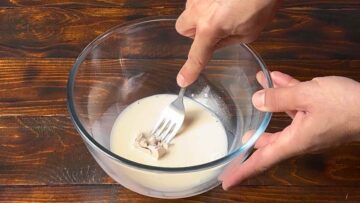 A bowl with milk, yeast and a fork.