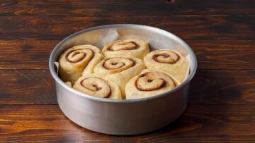 6 cinnamon buns in a pan after the rise.