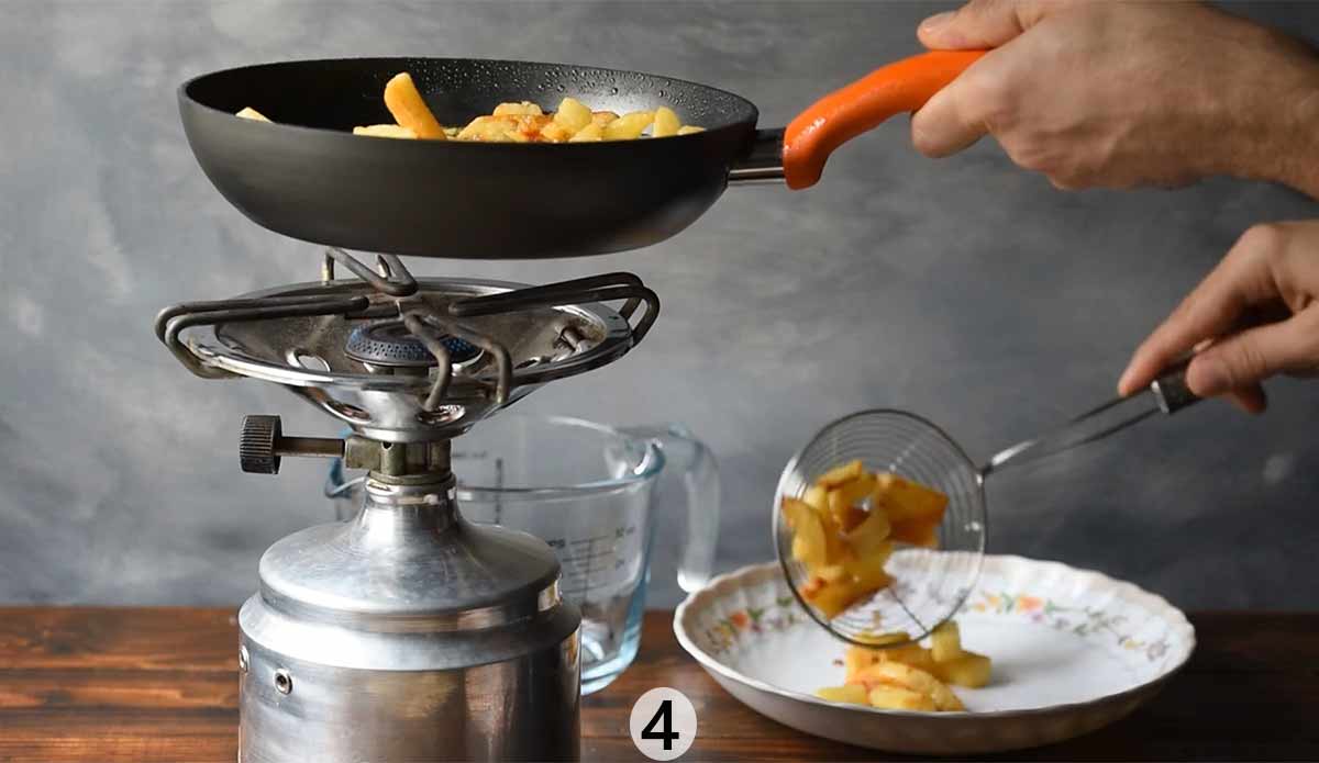 A man removing the fried potatoes from the frying pan.