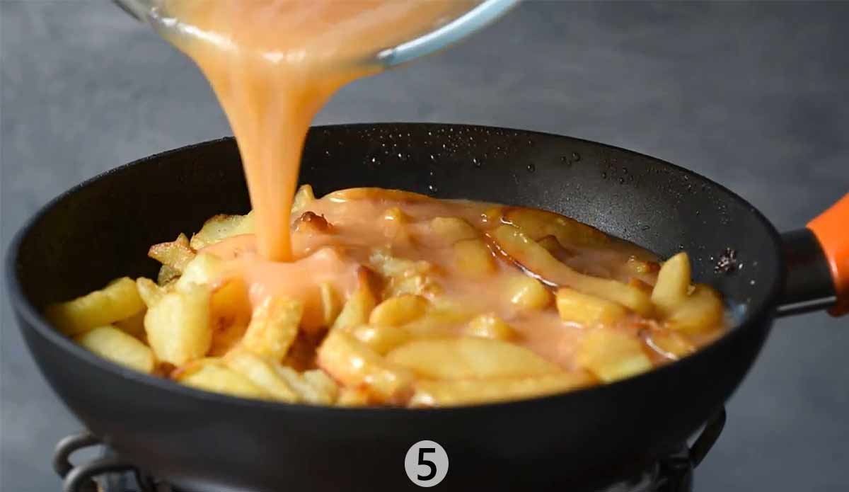 Pouring beaten eggs into the frying pan.