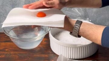 Two hands patting a yolk dry with paper towel.