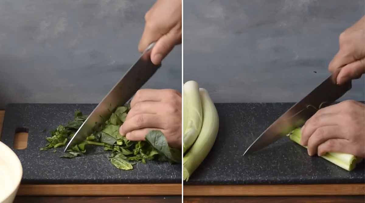 A hand chopping fresh spinach and leeks.