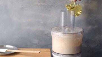 Adding oil to the food processor while it's running.