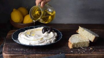 Drizzling olive oil over a plate with taramosalata.