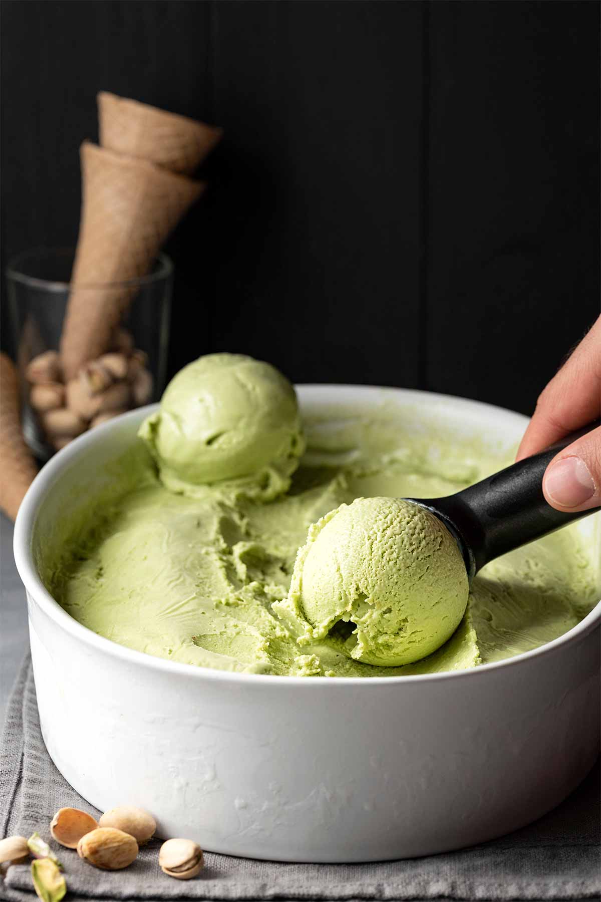 Pistachio ice cream in a container and an ice cream scoop.