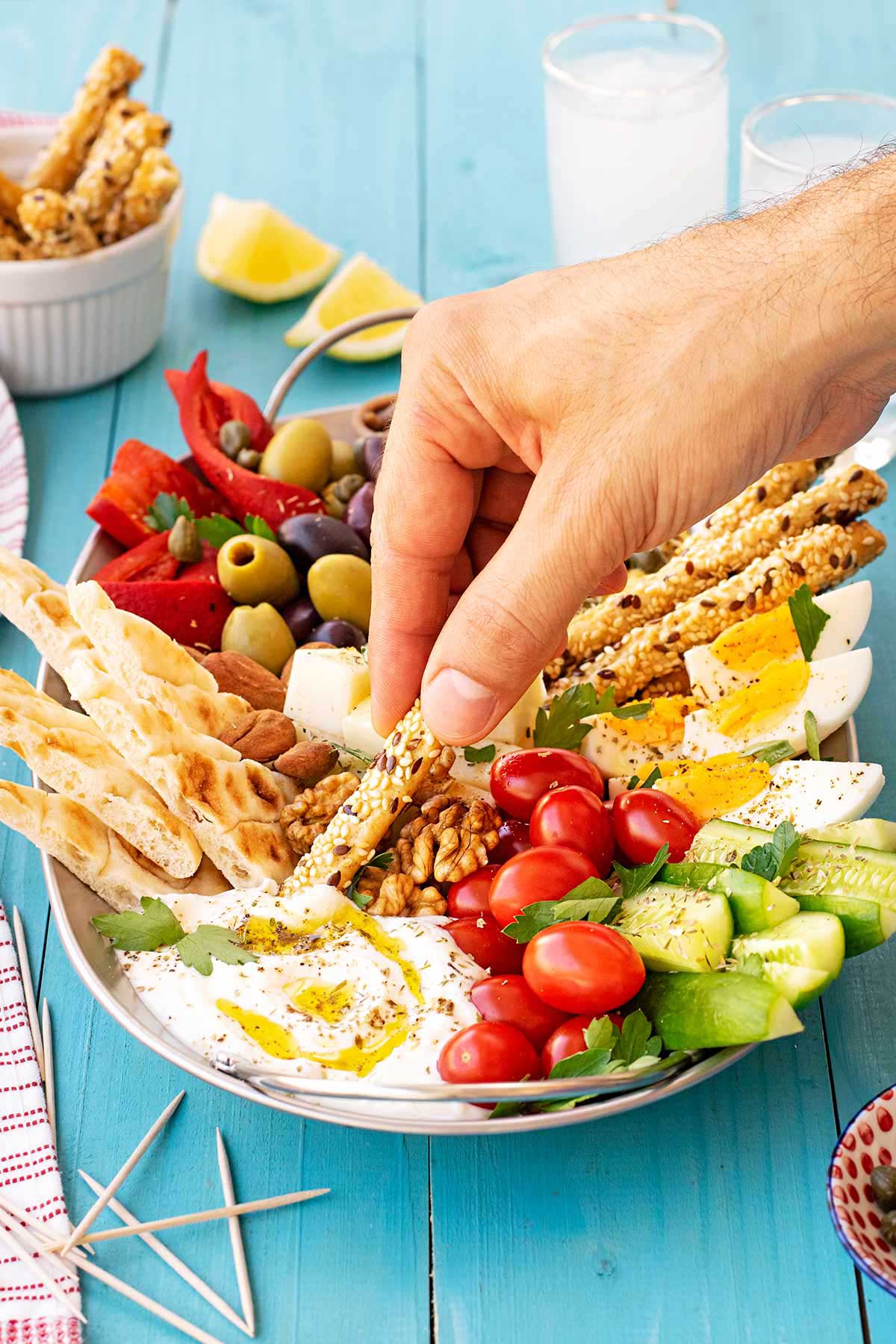 Greek mezze platter with pita bread, vegetables, Kalamata olives, fresh cheese dip and boiled eggs.