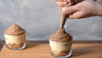 A hand piping sweet chestnut cream on top of the dessert.