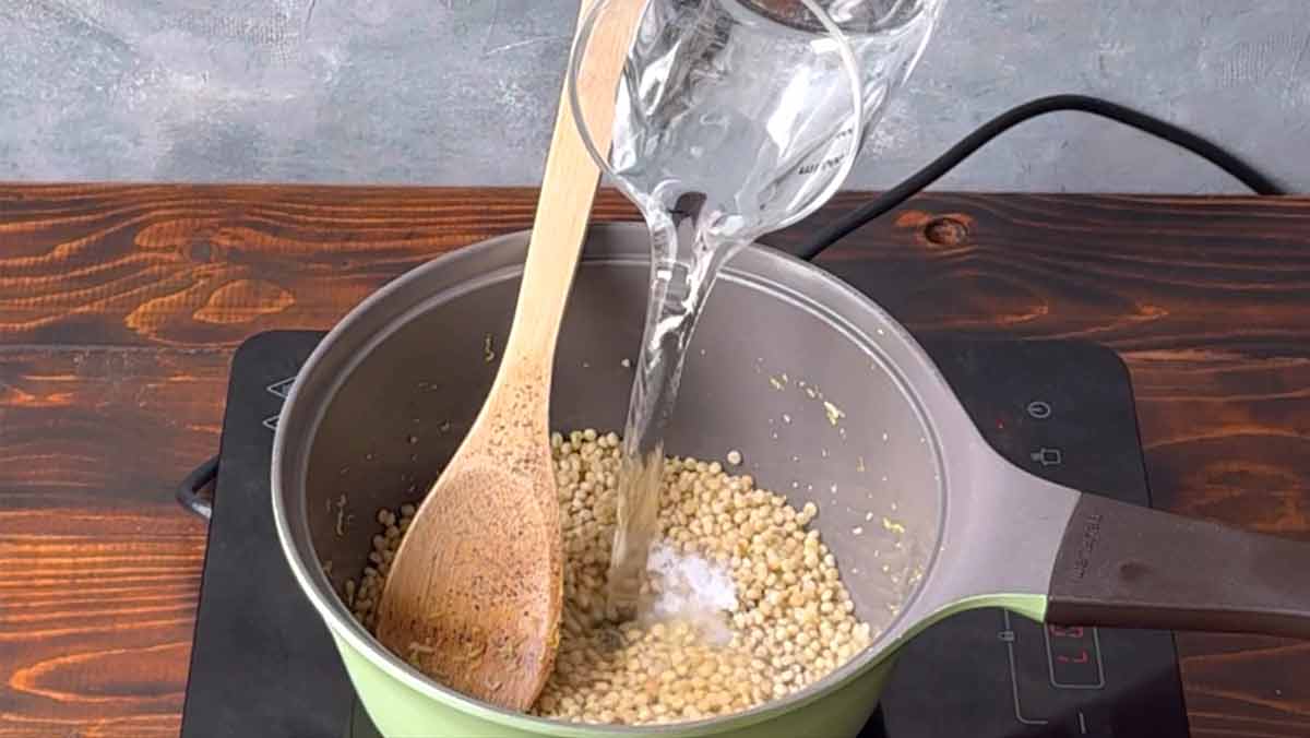 Adding water to the pot with the sauteed couscous.