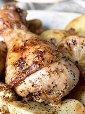 Baked chicken leg on a plate with potatoes, carrots and cauliflower.