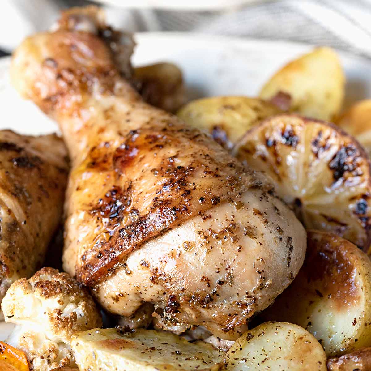 Baked chicken leg on a plate with potatoes, carrots and cauliflower.