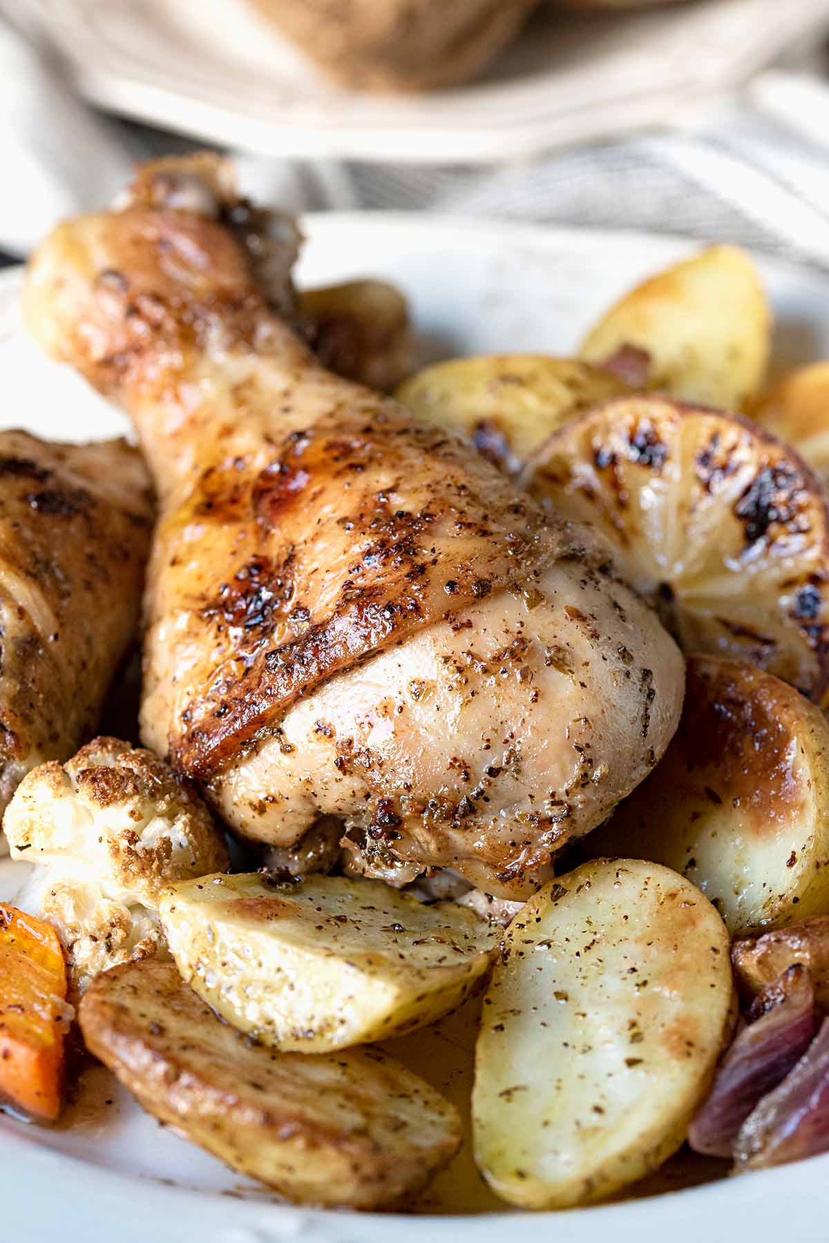 Baked chicken leg on a plate with potatoes, carrots and cauliflower.