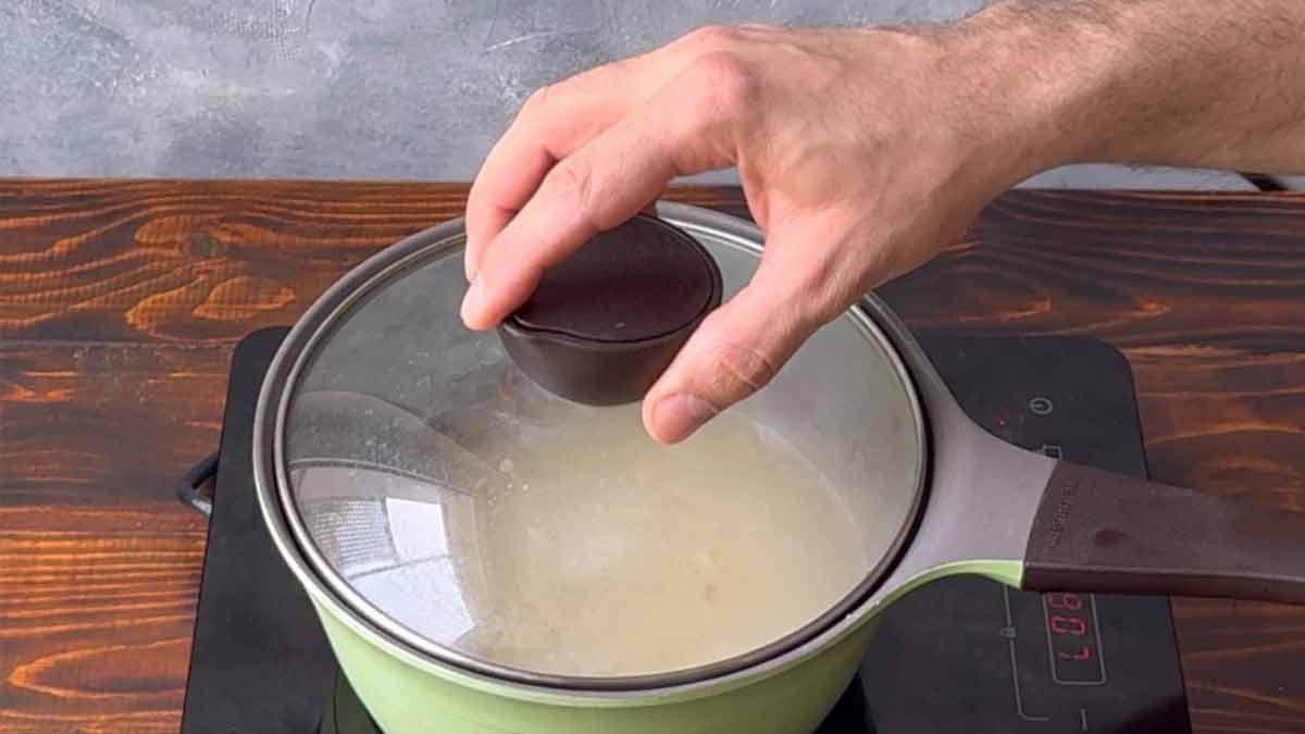 A hand placing the lid over the pot.