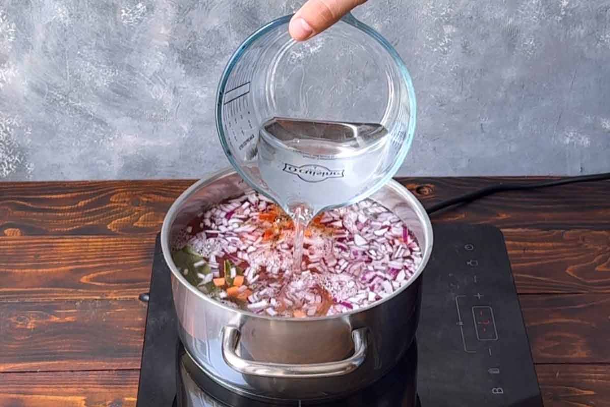 Adding water to the pot with the lentils.