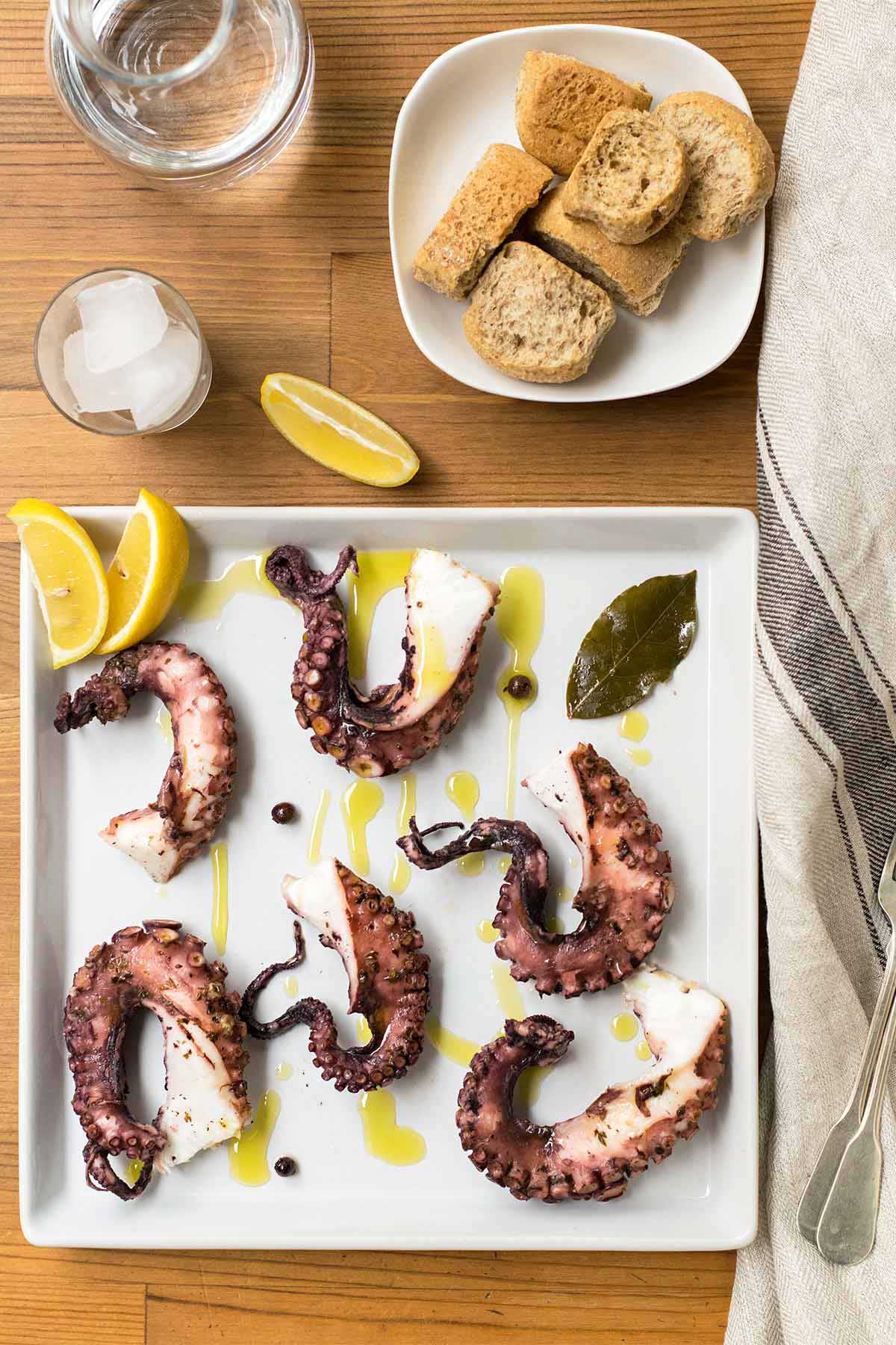 Mediterranean oven baked octopus cut in pieces and served with lemon wedges.