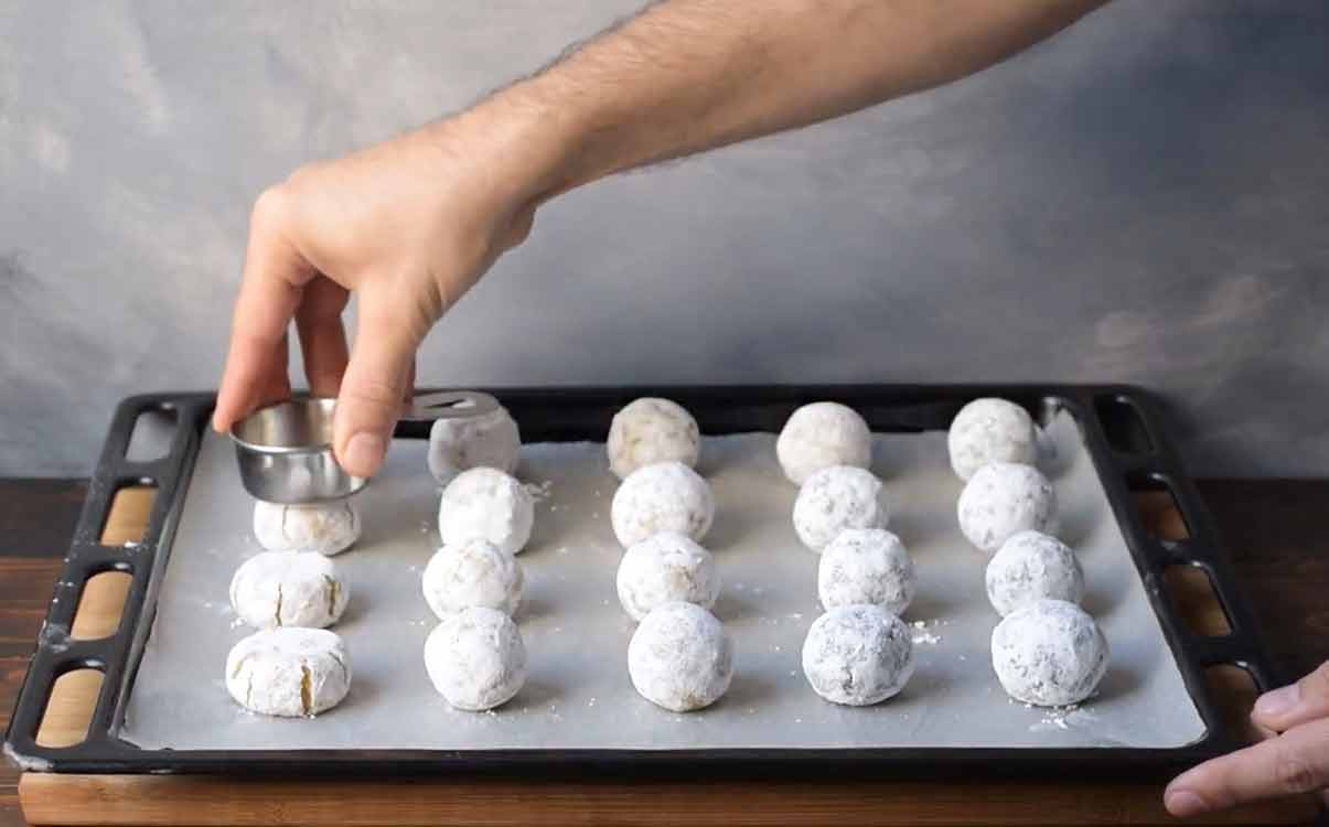 A hand flattening the cookies before baking.