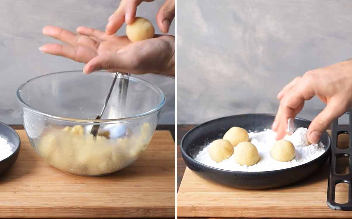 A hand rolling the almond cookies into balls.